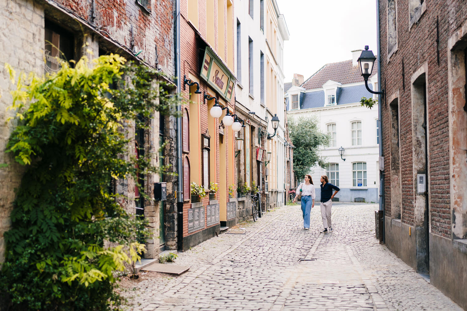 A cobbled medieval alleyway in Ghent's Patershol quarter, with eateries lined shoulder-to-shoulder along narrow streets.