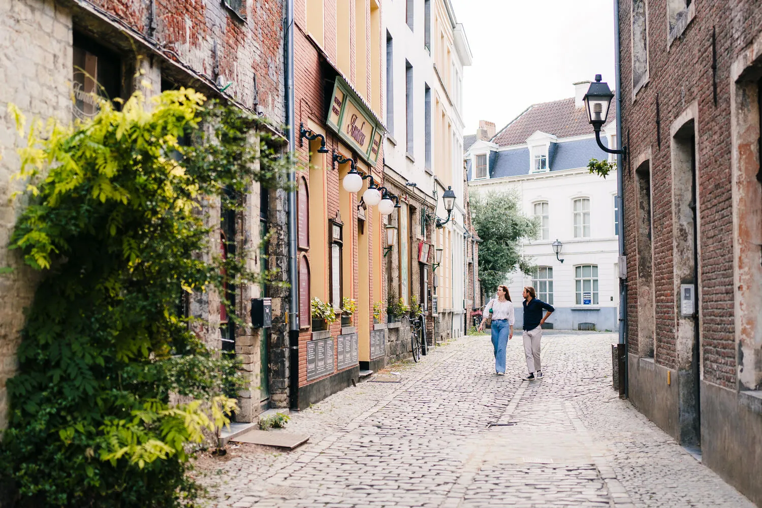 A cobbled medieval alleyway in Ghent's Patershol quarter, with eateries lined shoulder-to-shoulder along narrow streets.