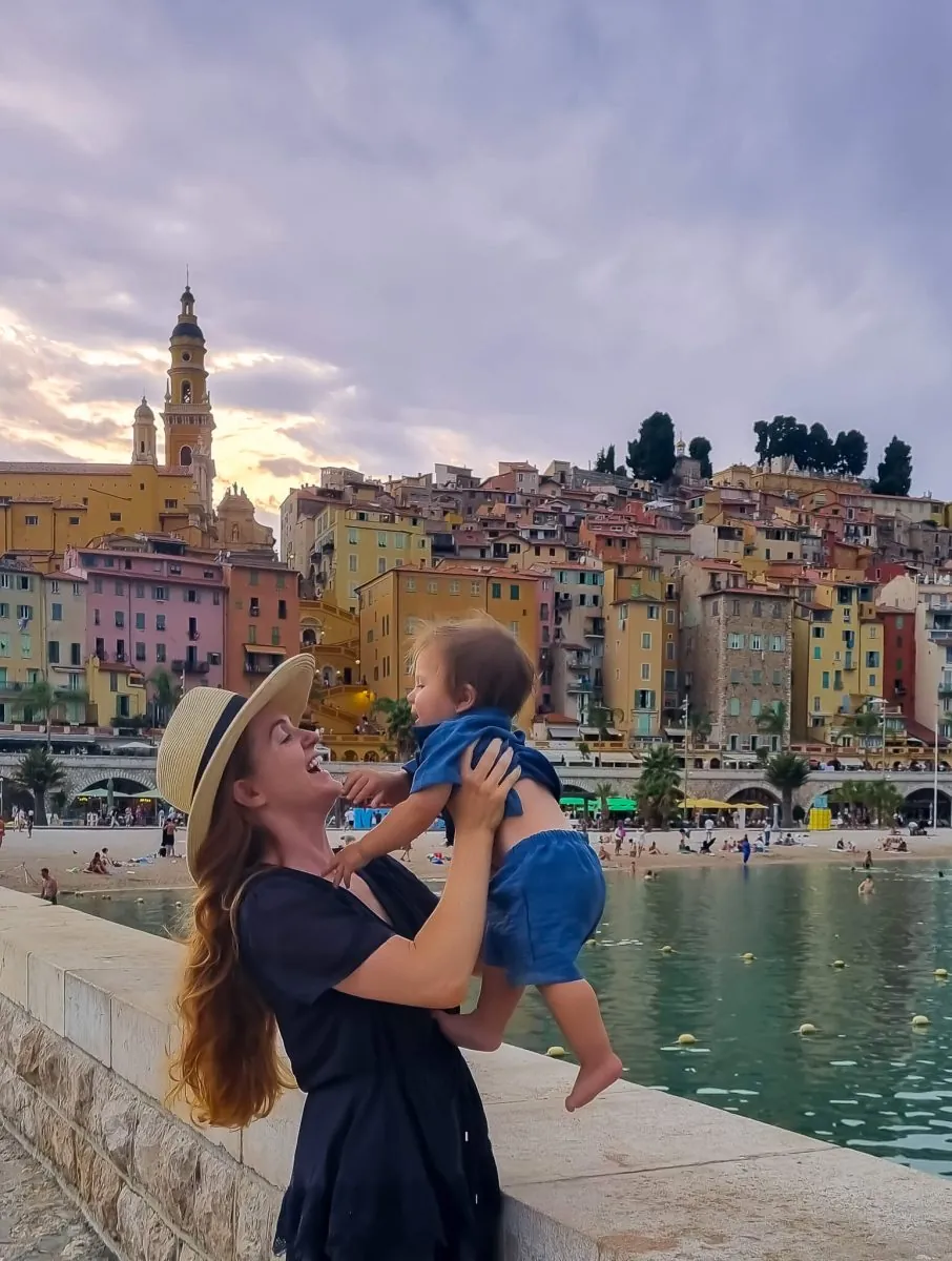 Menton old town from the Quai Impératrice Eugénie jetty — pastel houses stacked beneath the Basilique Saint-Michel