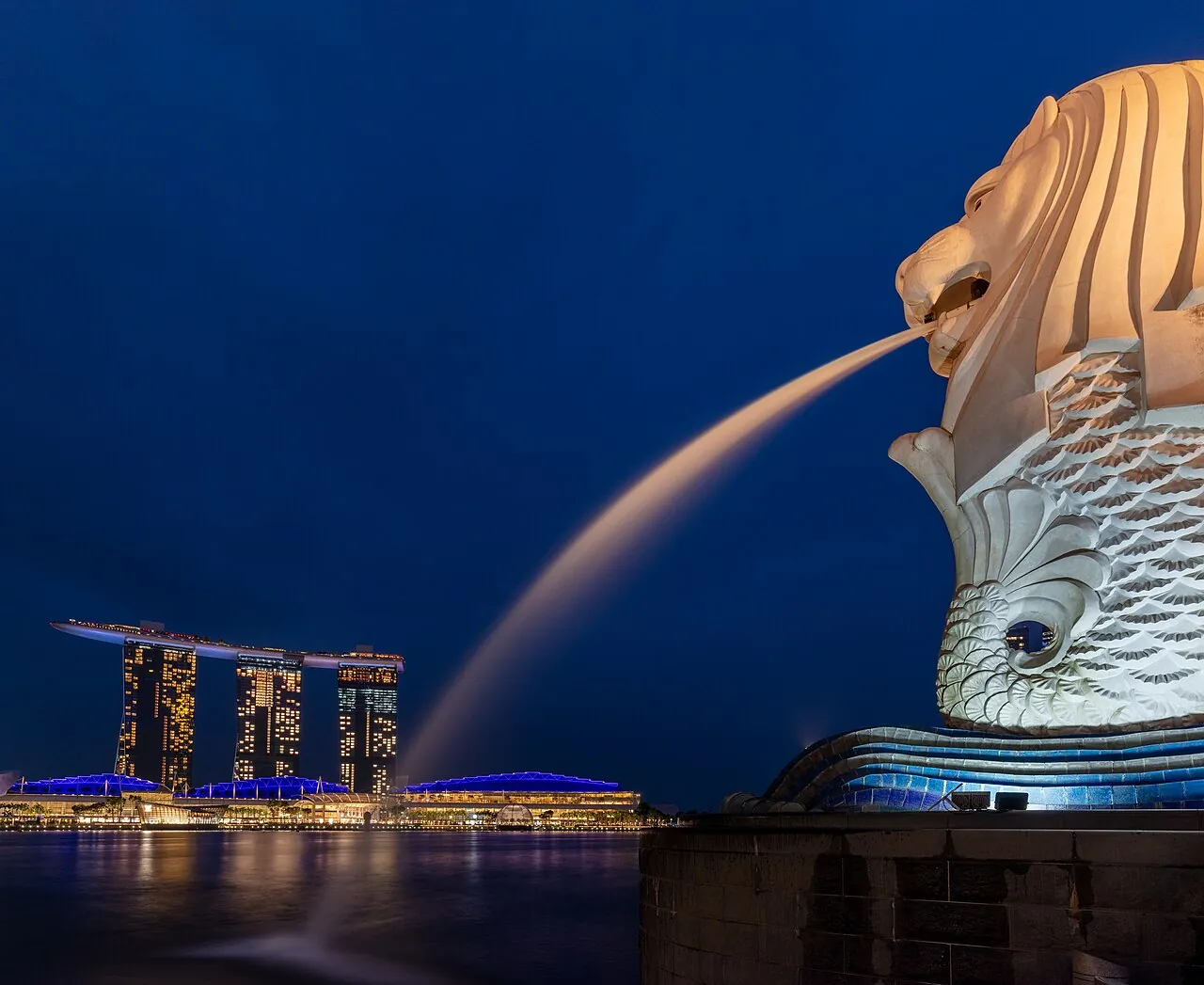 The Merlion statue spouting water with the city behind