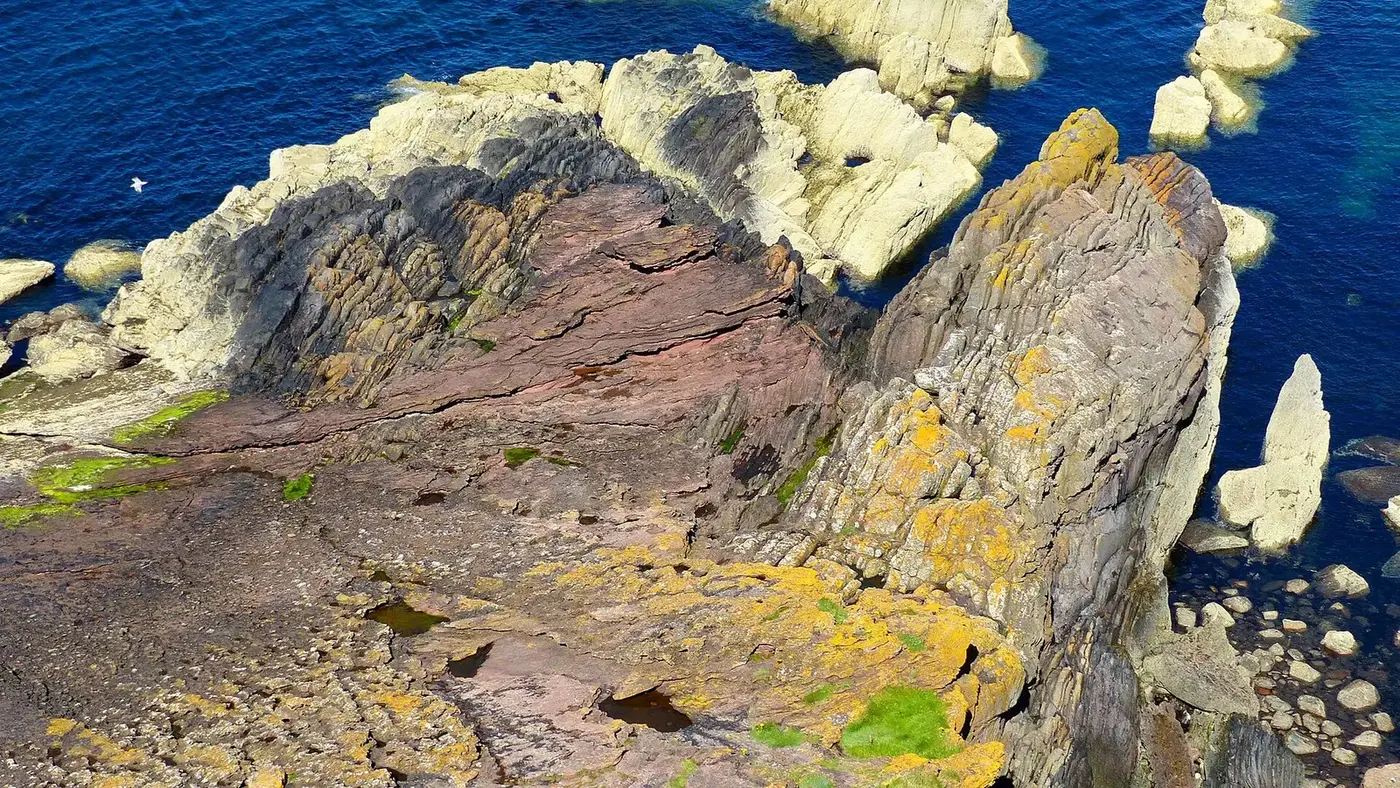 An angular unconformity in coastal rock: near-vertical beds truncated beneath a flat-lying layer
