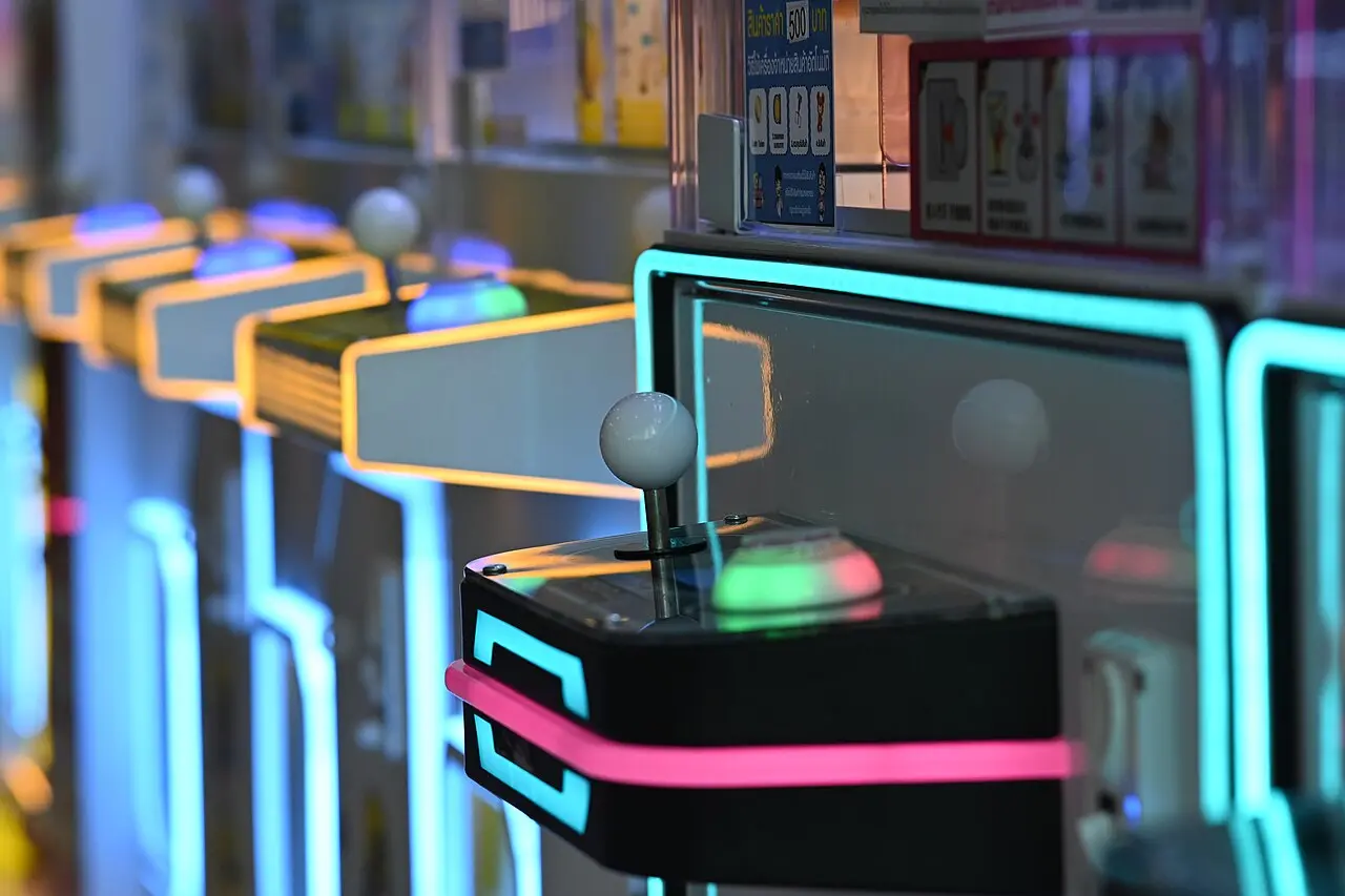 Close-up of a row of retro arcade joysticks lit in blue and pink