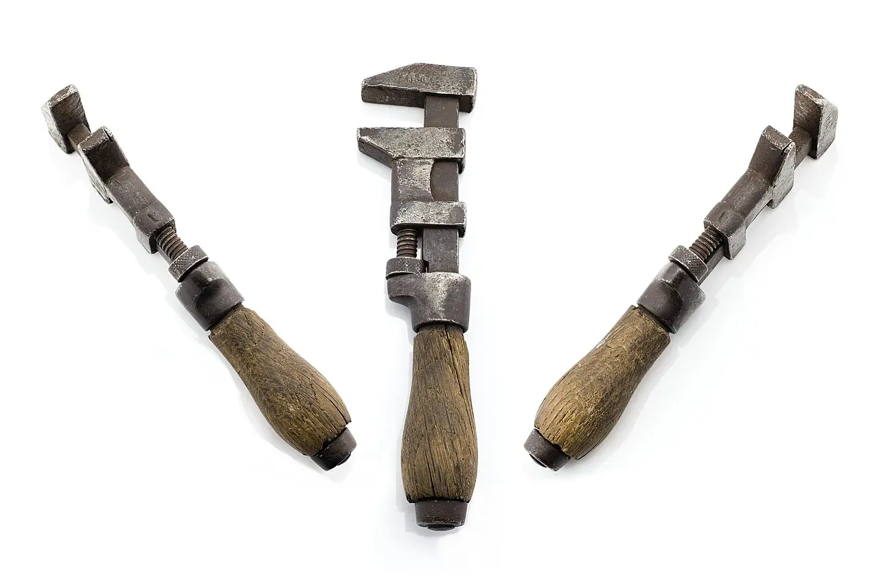 A worn monkey wrench photographed against a plain ground