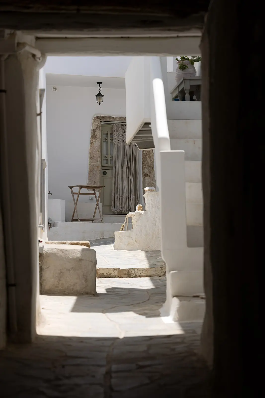 A whitewashed archway framing a marble-paved lane and stone doorway in Naxos Chora