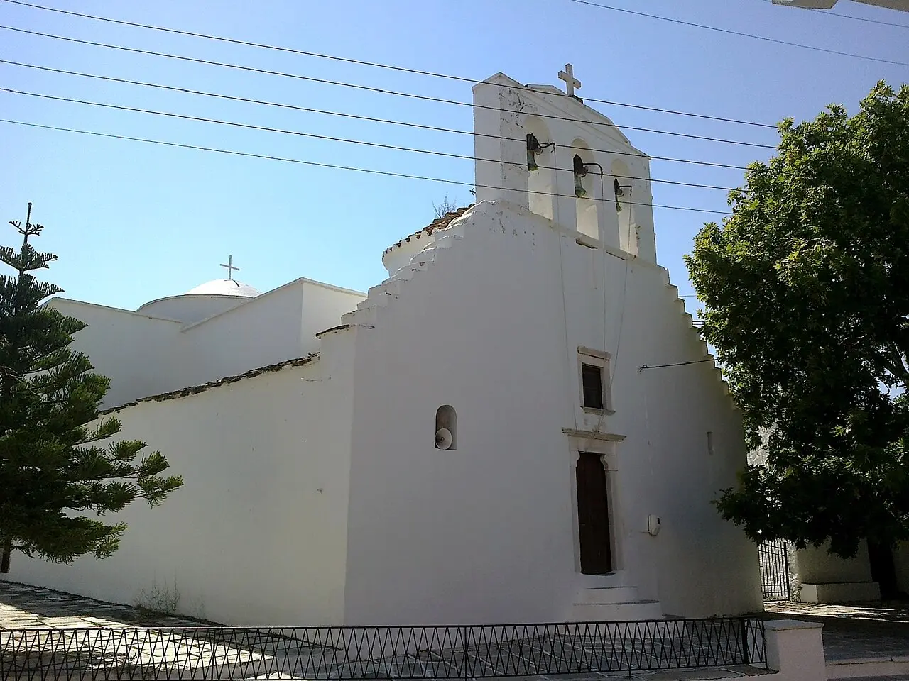 Panagia Protothroni church in Halki, Naxos, whitewashed with a stone bell gable among trees